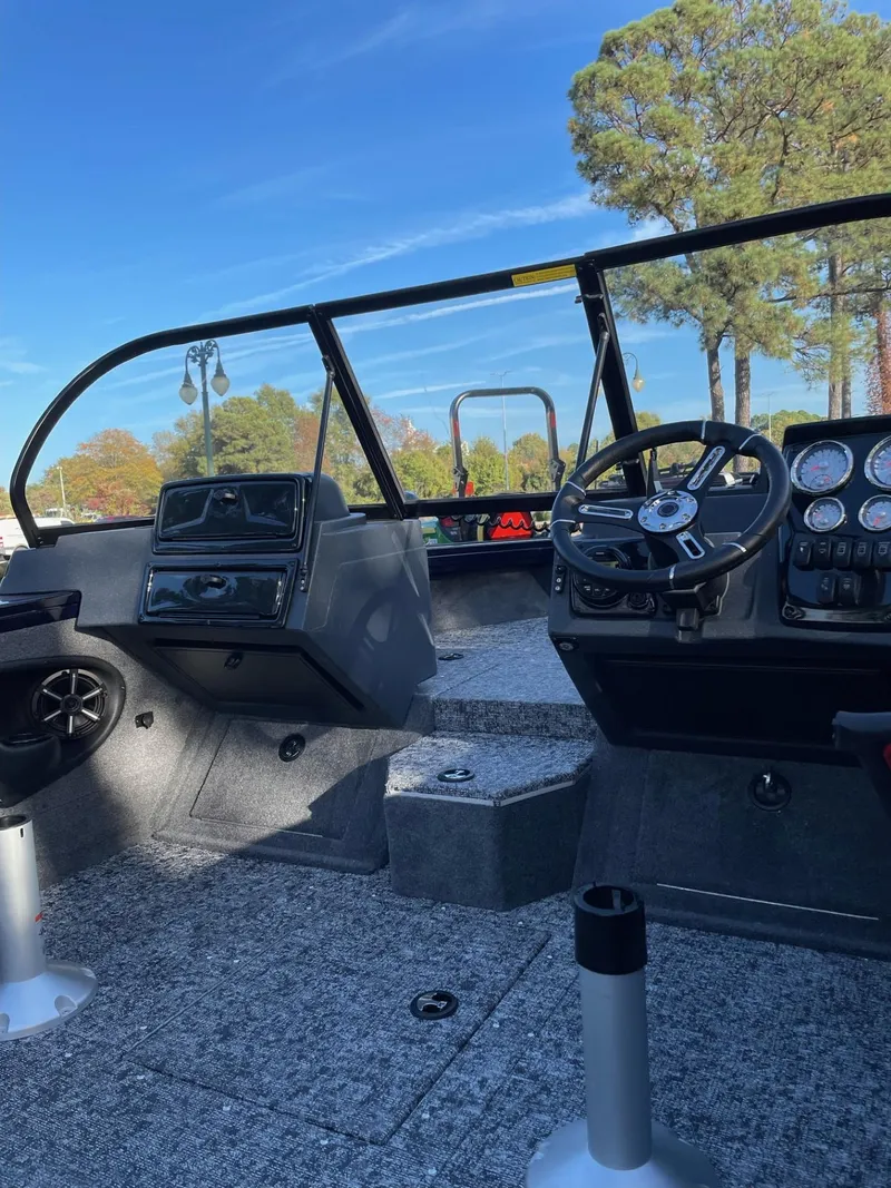 Slide: The Image of 2025 Tracker Targa V-18 WT boat interior with steering wheel and dashboard, under clear blue sky. - 3