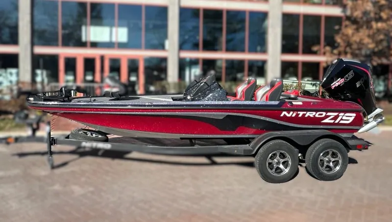 Slide: The Image of 2025 Nitro Z19 boat on trailer, parked outdoors, surrounded by trees. - 1