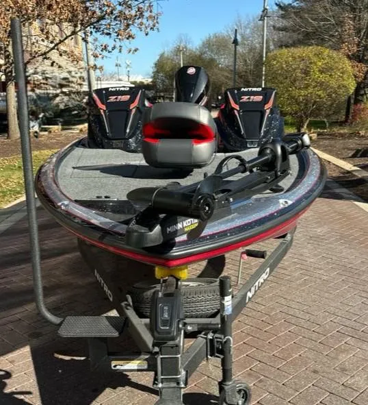 Slide: The Image of 2025 Nitro Z19 fishing boat with dual seats and trolling motor, parked on brick pavement. - 2