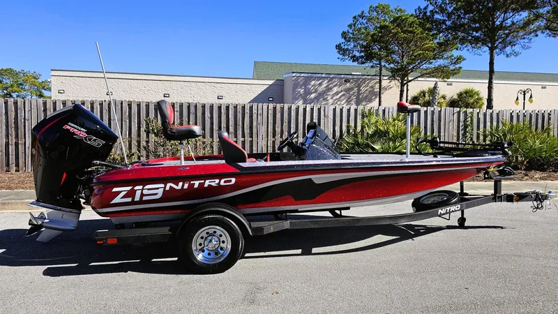 The Image of 2025 Nitro Z19 boat, red and black design, parked outdoors. - 0