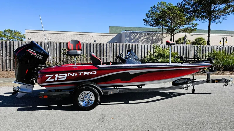 Slide: The Image of 2025 Nitro Z19 boat, red and black, parked outdoors on a trailer. - 2