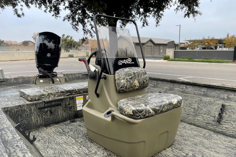 Slide: The Image of 2025 Tracker Grizzly 2072 CC boat with camouflage seats and console, parked outdoors. - 5