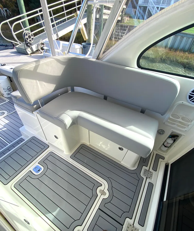 Slide: The Image of 2004 Pursuit 3100 Offshore boat with gray cushioned seating and non-slip deck flooring. - 12