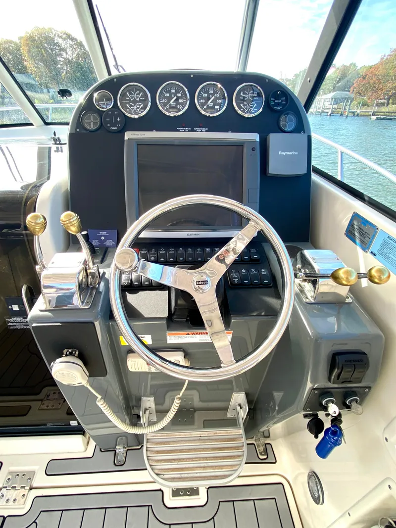 Slide: The Image of 2004 Pursuit 3100 Offshore boat helm with steering wheel and control panel. - 14