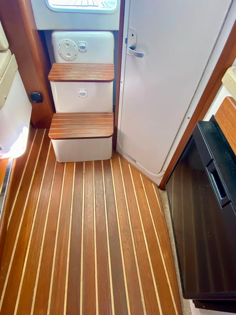 Slide: The Image of 2004 Pursuit 3100 Offshore cabin interior with wooden flooring and steps. - 17