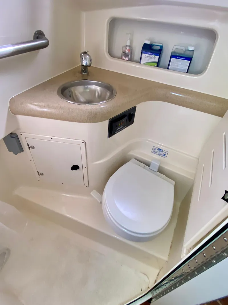 Slide: The Image of 2004 Pursuit 3100 Offshore boat bathroom with sink, toilet, and storage shelves. - 23