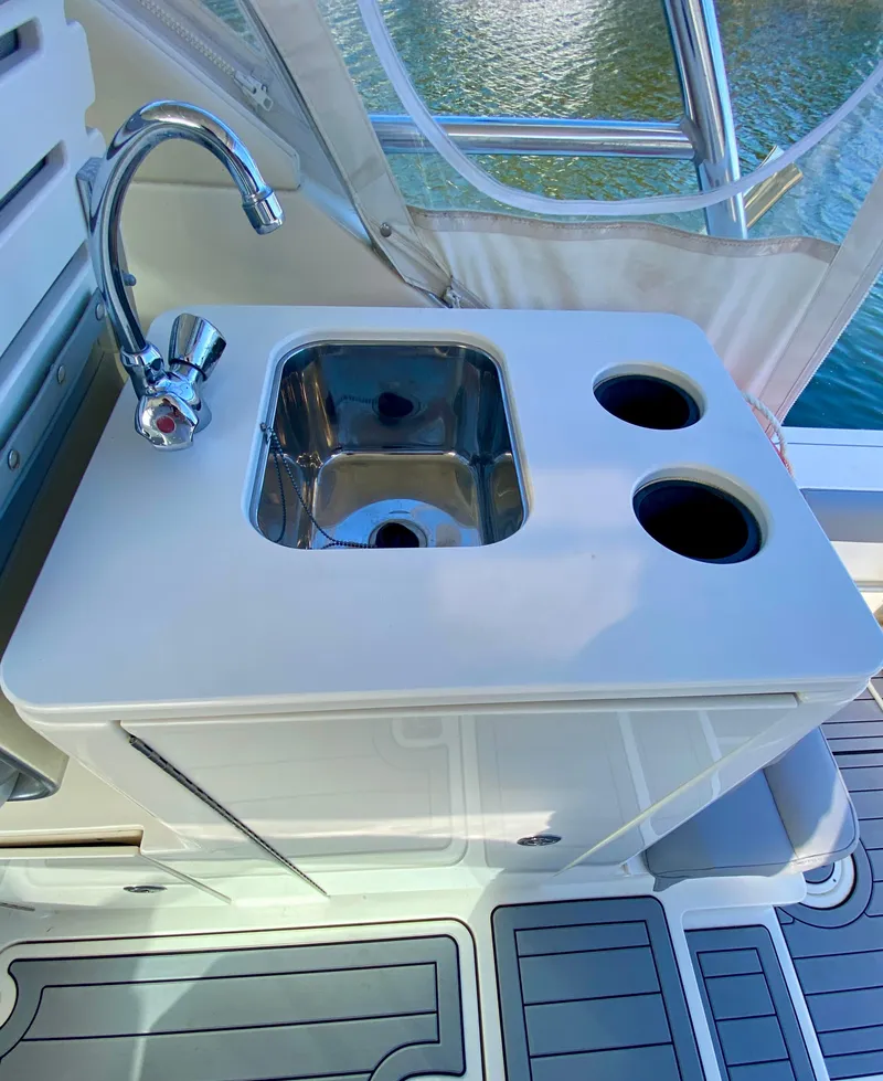 Slide: The Image of 2004 Pursuit 3100 Offshore boat sink with faucet and cup holders on deck. - 8