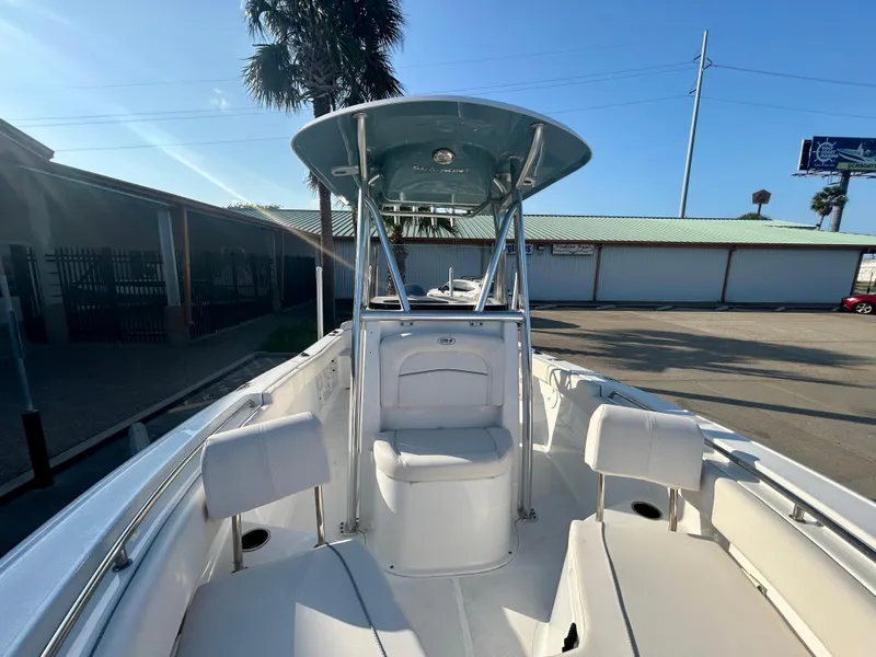 Slide: The Image of 2023 Sea Hunt Ultra 219 boat with T-top, docked under clear blue sky. - 13
