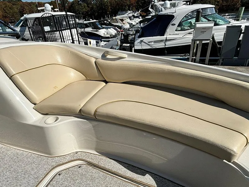 Slide: The Image of 2002 Sea Ray 240 Sundeck with beige seating, docked among other boats. - 17