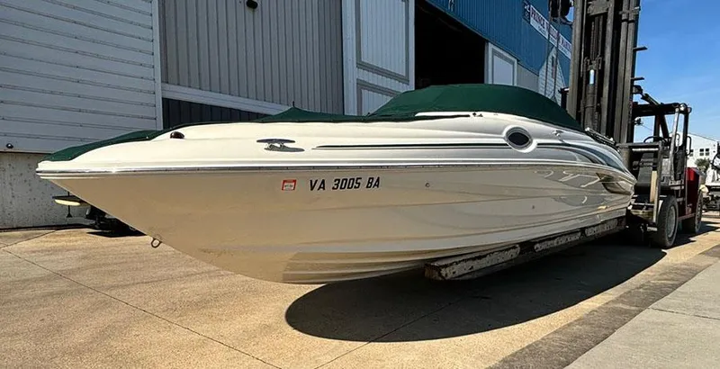 Slide: The Image of 2002 Sea Ray 240 Sundeck boat on forklift, white hull, green cover, dockside. - 3