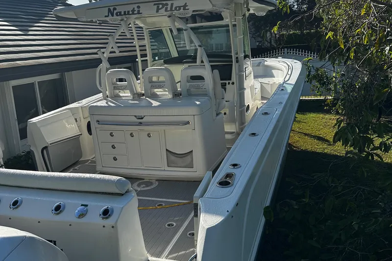 Slide: The Image of 2014 Boston Whaler 370 Outrage boat with white seating and storage, docked near a house. - 5