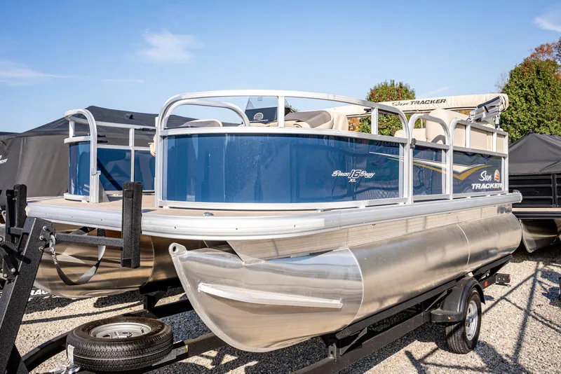 The Image of 2025 Sun Tracker Bass Buggy 16 DLX pontoon boat on trailer, blue and silver design. - 1