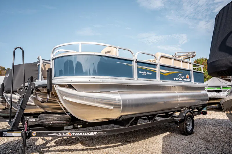 The Image of 2025 Sun Tracker BASS BUGGY 18 pontoon boat on trailer, parked outdoors. - 1