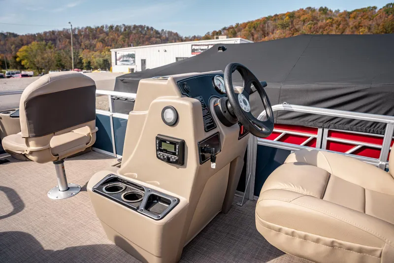 Slide: The Image of 2025 Sun Tracker BASS BUGGY 18 pontoon boat interior with beige seating and steering console. - 10