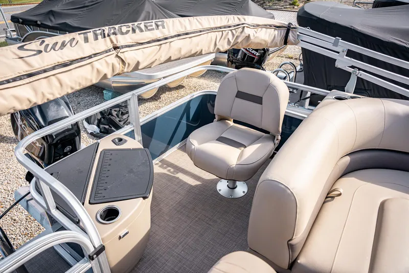 Slide: The Image of 2025 Sun Tracker BASS BUGGY 18 pontoon boat interior with beige seating and console. - 13