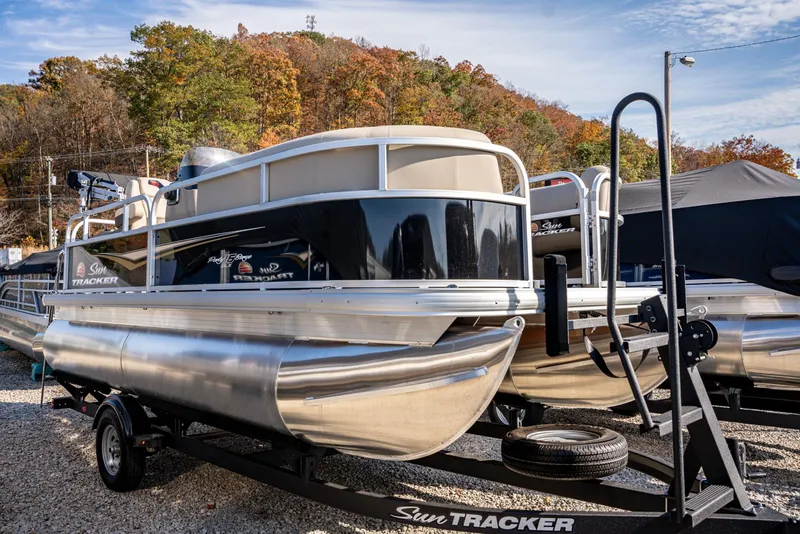 The Image of 2025 Sun Tracker Party Barge 16 pontoon boat on trailer, parked outdoors. - 1