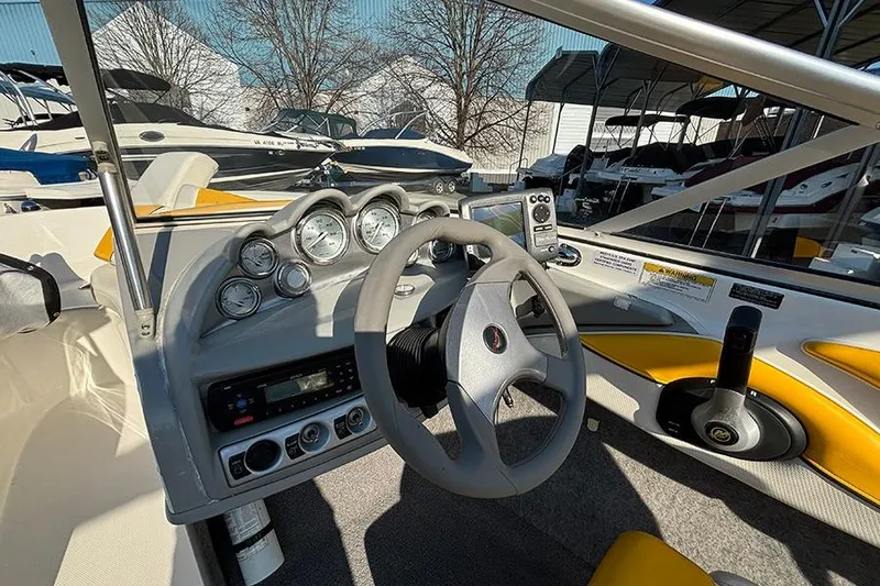 Slide: The Image of 2012 Bayliner 185 Bowrider dashboard with steering wheel and gauges in a marina setting. - 10