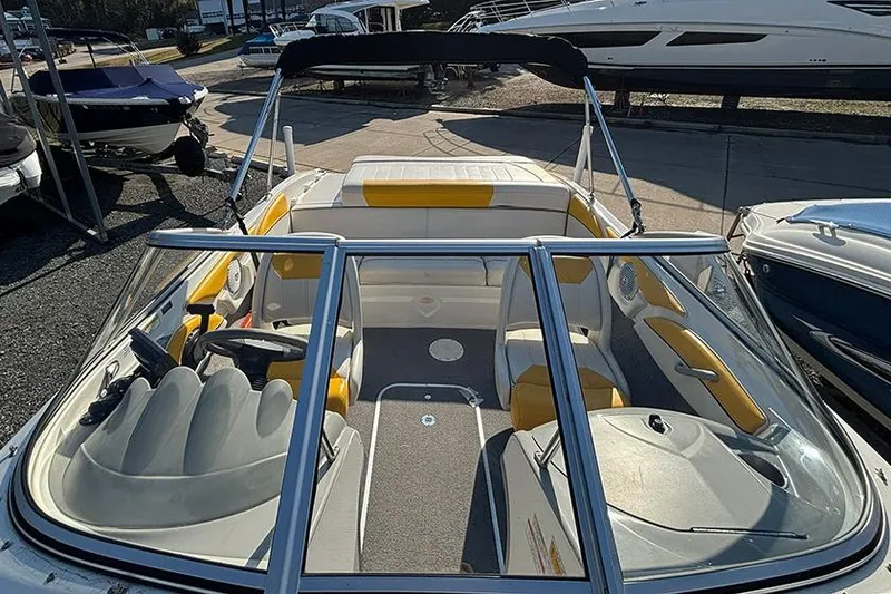 Slide: The Image of 2012 Bayliner 185 Bowrider boat interior with seating and steering wheel, docked outdoors. - 13