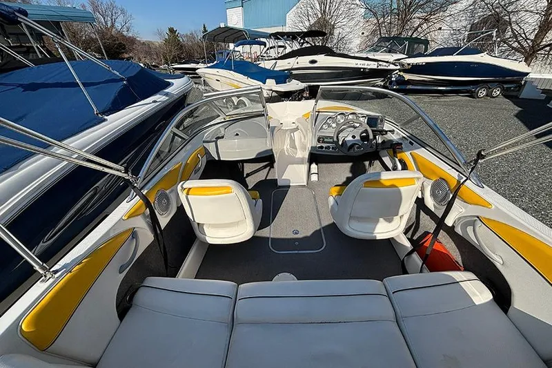 Slide: The Image of 2012 Bayliner 185 Bowrider interior with yellow accents, parked among other boats. - 19
