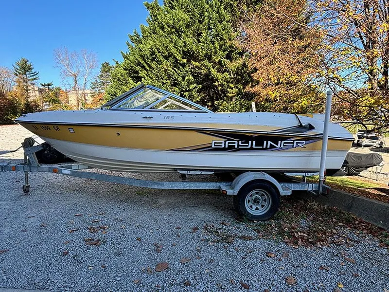 Slide: The Image of 2012 Bayliner 185 Bowrider boat on trailer, parked outdoors in autumn setting. - 2