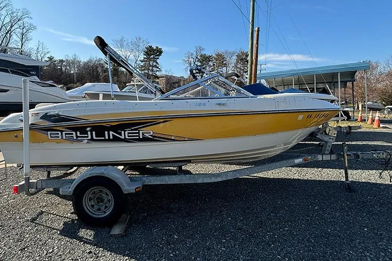 Slide: The Image of 2012 Bayliner 185 Bowrider boat on trailer, yellow and white, parked outdoors. - 4