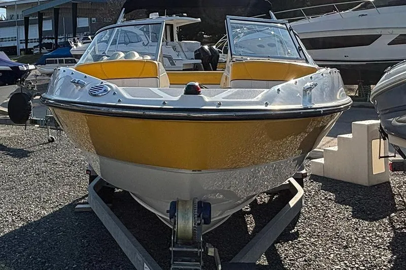 Slide: The Image of 2012 Bayliner 185 Bowrider boat with yellow hull on trailer, parked outdoors. - 5