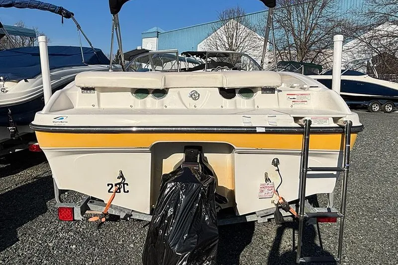 Slide: The Image of 2012 Bayliner 185 Bowrider boat, rear view, parked on gravel with ladder and cover. - 6