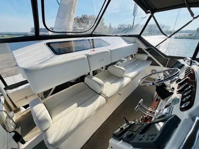 Slide: The Image of Interior of 1999 Silverton 392 Motor Yacht with white seating and control panel. - 12