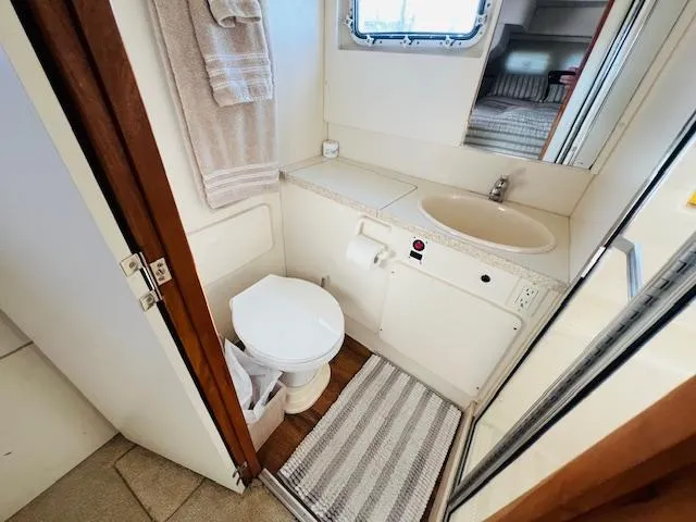 Slide: The Image of 1999 Silverton 392 Motor Yacht bathroom with toilet, sink, and window. - 26