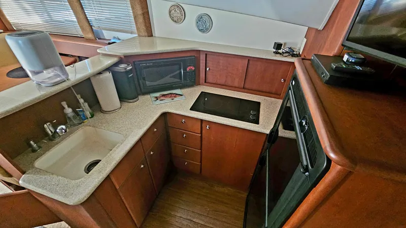 Slide: The Image of 2005 Silverton 330 Sport Bridge kitchen with sink, microwave, and wooden cabinetry. - 10