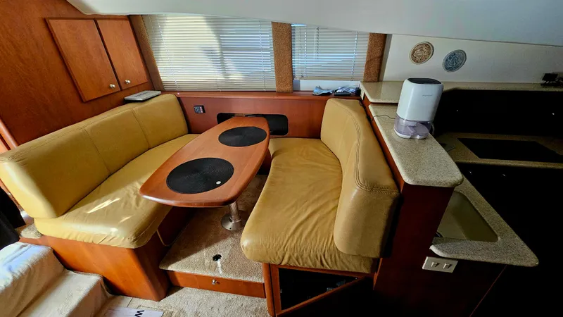 Slide: The Image of Interior of 2005 Silverton 330 Sport Bridge with beige seating and wooden table. - 8