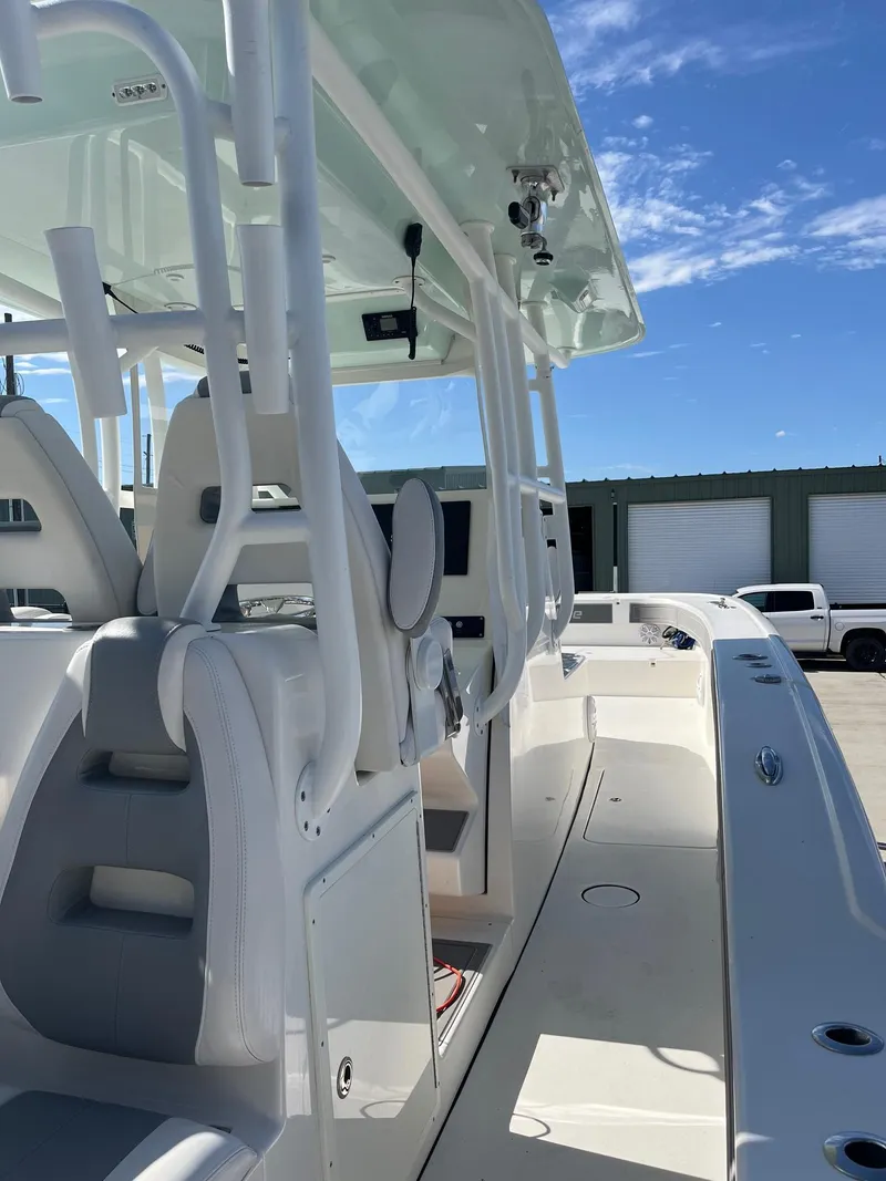 Slide: The Image of 2021 Tideline 365 boat interior with modern seating and controls under a clear blue sky. - 24