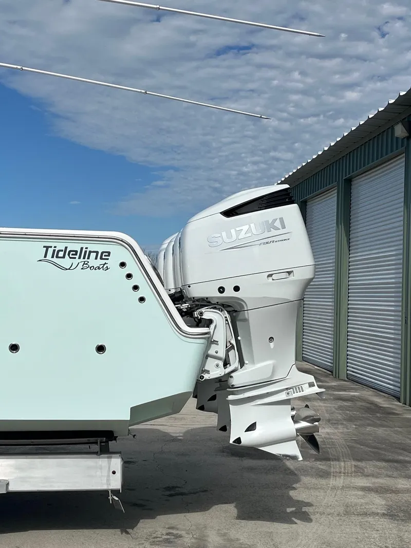 Slide: The Image of Tideline 365 boat with Suzuki outboard motor, parked near storage units, under a partly cloudy sky. - 36