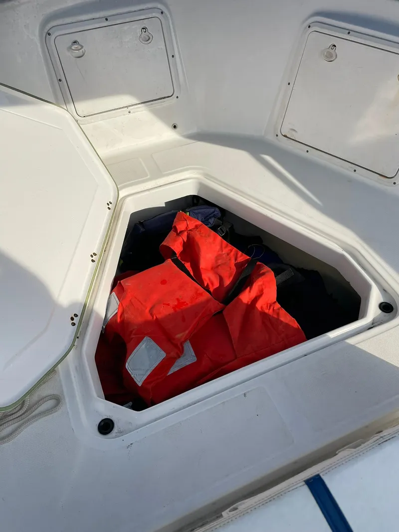 Slide: The Image of Open storage compartment on 2000 Edgewater 247CC boat with red life jackets inside. - 25