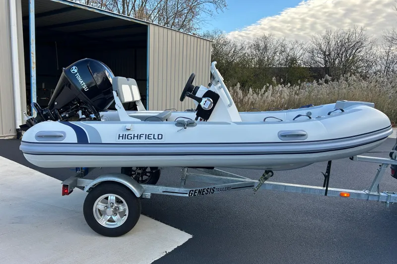 Slide: The Image of 2026 Highfield Classic 360 GT inflatable boat on trailer, featuring Tohatsu outboard motor. - 11