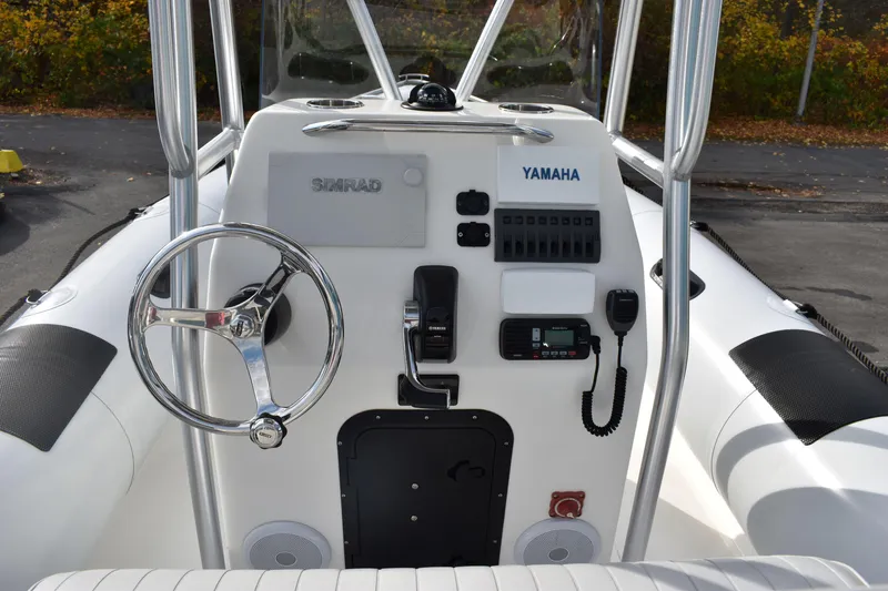 Slide: The Image of 2015 Ribcraft 7.8 boat with seating and canopy, docked near a black wall. - 1