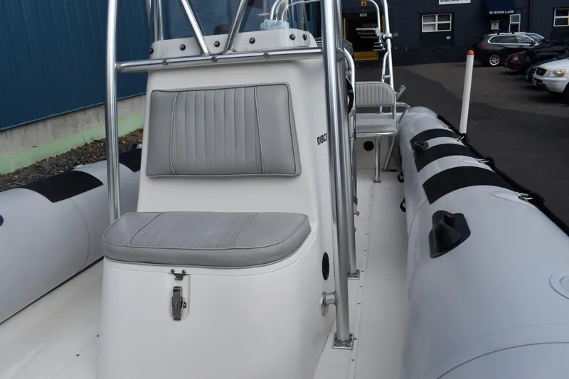 Slide: The Image of 2015 Ribcraft 7.8 boat interior with seating and motor, parked on a paved area. - 7