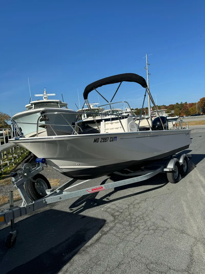 Slide: The Image of 2024 Boston Whaler 190 Montauk boat on trailer, parked outdoors under clear blue sky. - 16
