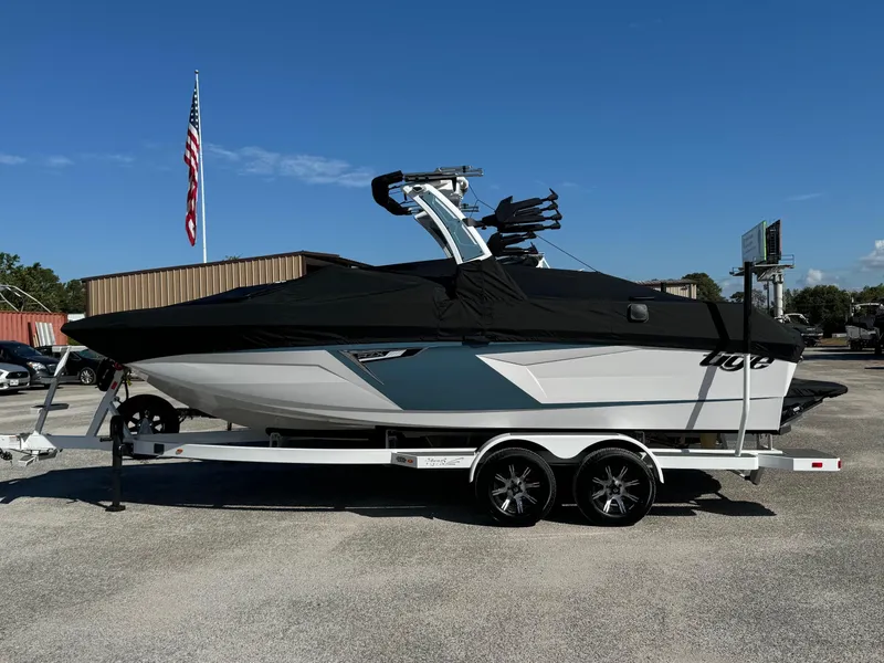 Slide: The Image of 2025 Tigé 22RZX boat on trailer, covered, with American flag in background. - 15