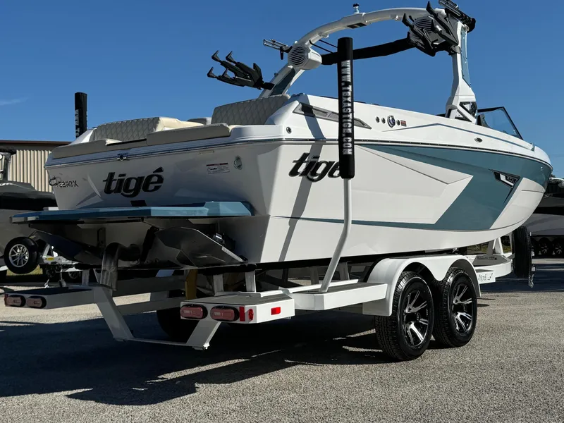 Slide: The Image of 2025 Tigé 22RZX boat on trailer, sleek design, dual axle, sunny day. - 4