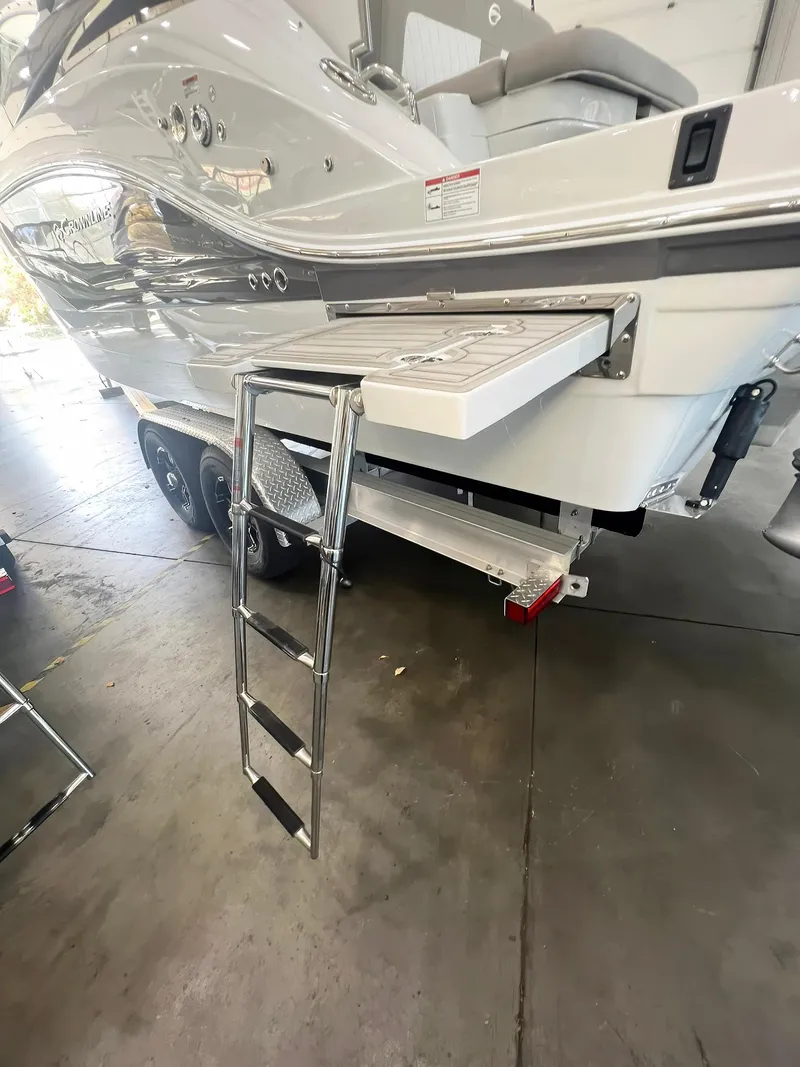 Slide: The Image of 2025 Crownline 280 CRX boat with extended swim platform and ladder in showroom. - 2