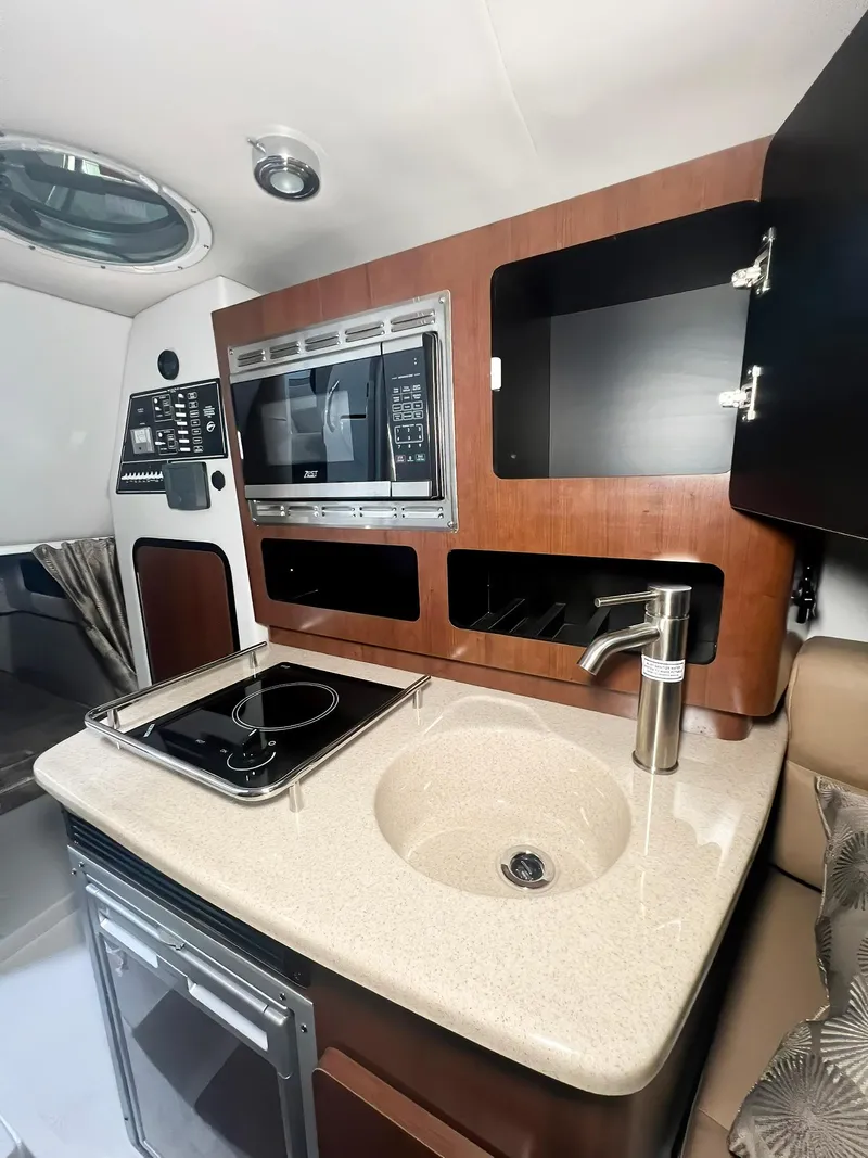 Slide: The Image of 2025 Crownline 280 CRX yacht interior with kitchenette, featuring sink, stove, and microwave. - 28