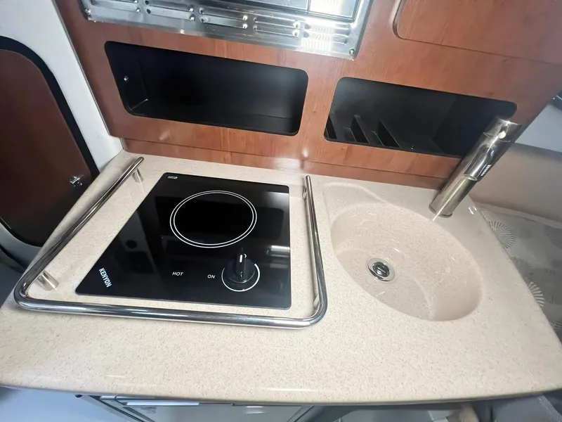 Slide: The Image of 2025 Crownline 280 CRX boat kitchenette with stove and sink. - 29