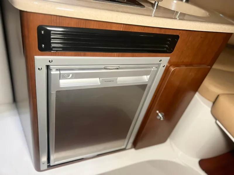 Slide: The Image of 2025 Crownline 280 CRX boat interior with compact refrigerator and wooden cabinetry. - 38