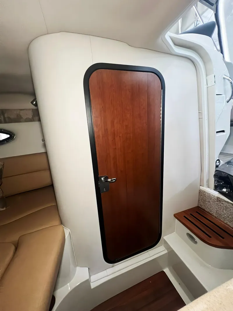 Slide: The Image of 2025 Crownline 280 CRX cabin interior with wooden door and beige seating. - 39