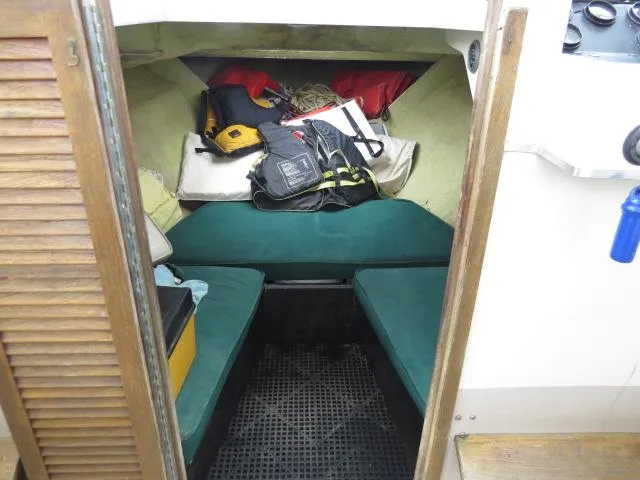Slide: The Image of 1973 Slickcraft SS235 boat cabin with green cushions and storage items. - 16