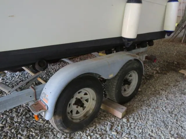 Slide: The Image of 1973 Slickcraft SS235 boat on trailer with dual wheels, parked on gravel. - 24