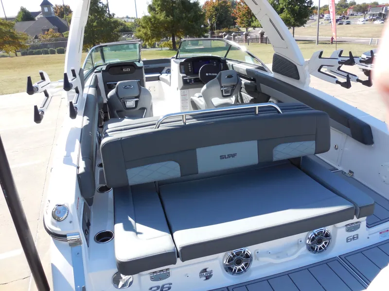 Slide: The Image of 2025 Chaparral 26 Surf boat interior with seating and dashboard, parked outdoors. - 7