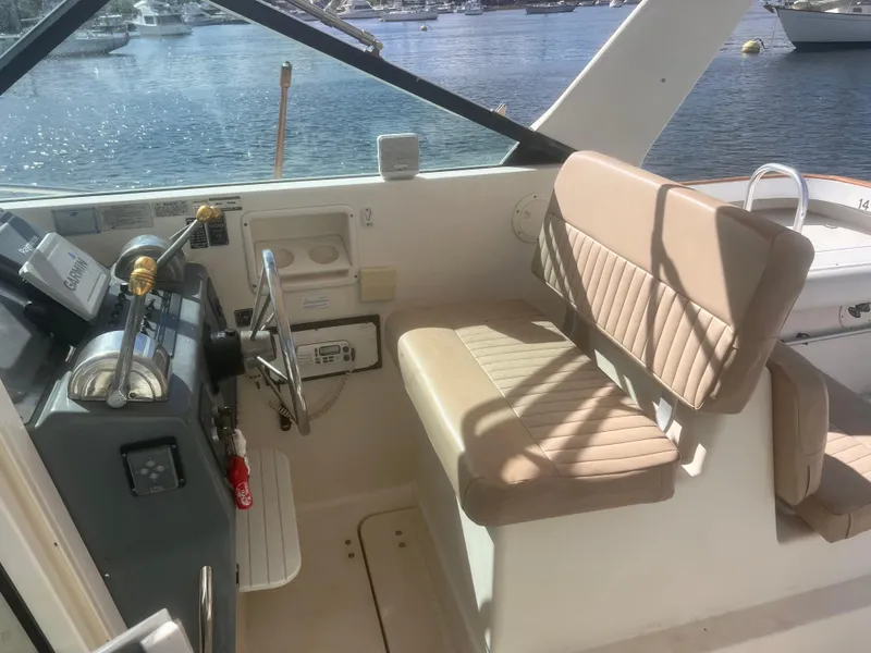 Slide: The Image of 1995 Tiara Yachts 2900 Open cockpit with beige seating and steering wheel, overlooking marina. - 15