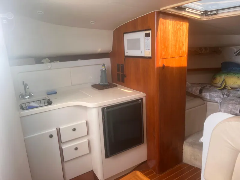 Slide: The Image of 1995 Tiara Yachts 2900 Open cabin interior with kitchenette and cozy sleeping area. - 23